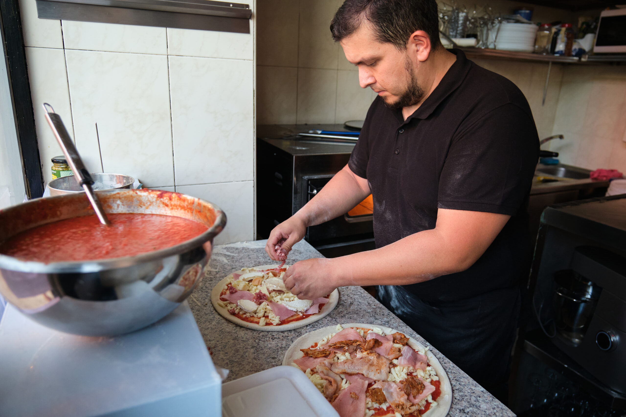 Latin man preparing pizzas in a restaurant kitchen. Pizzeria.