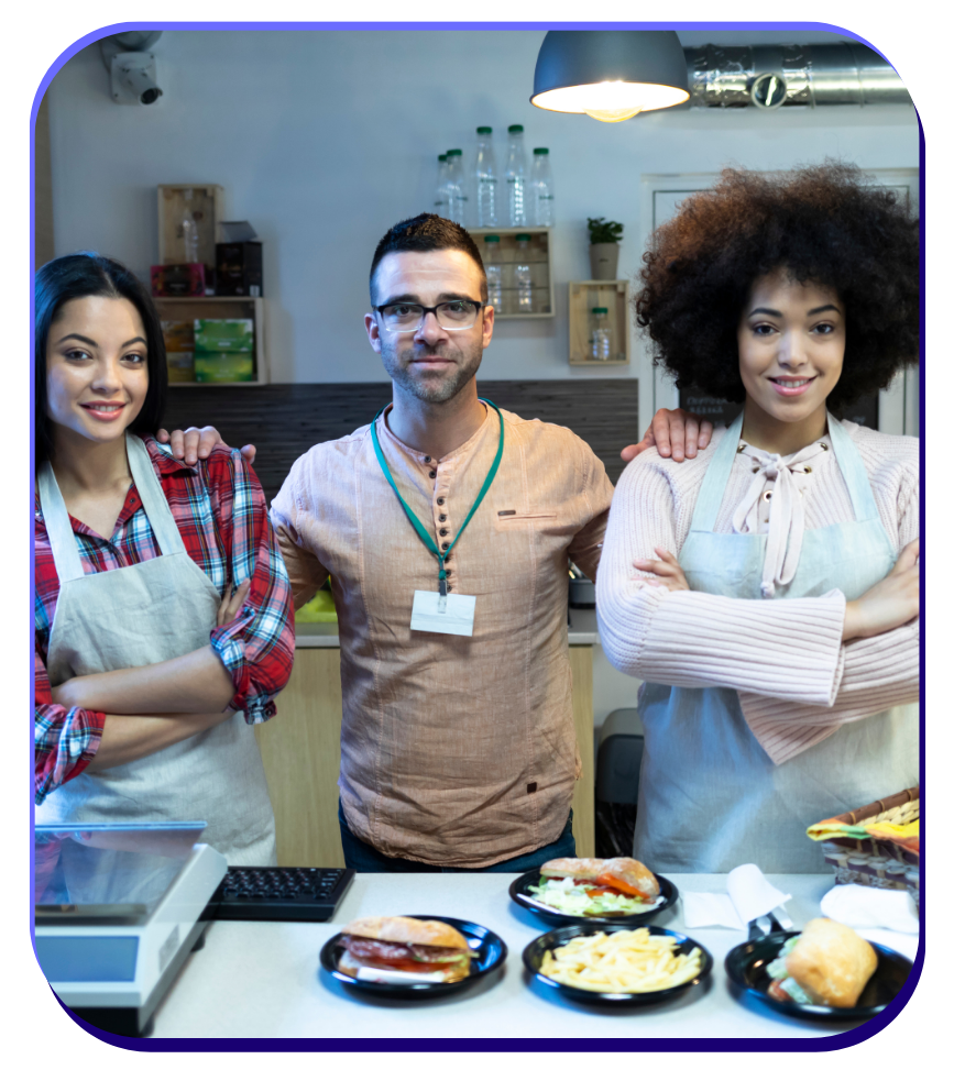 Three restaurant workers standing and smiling with their quick service sandwich shop