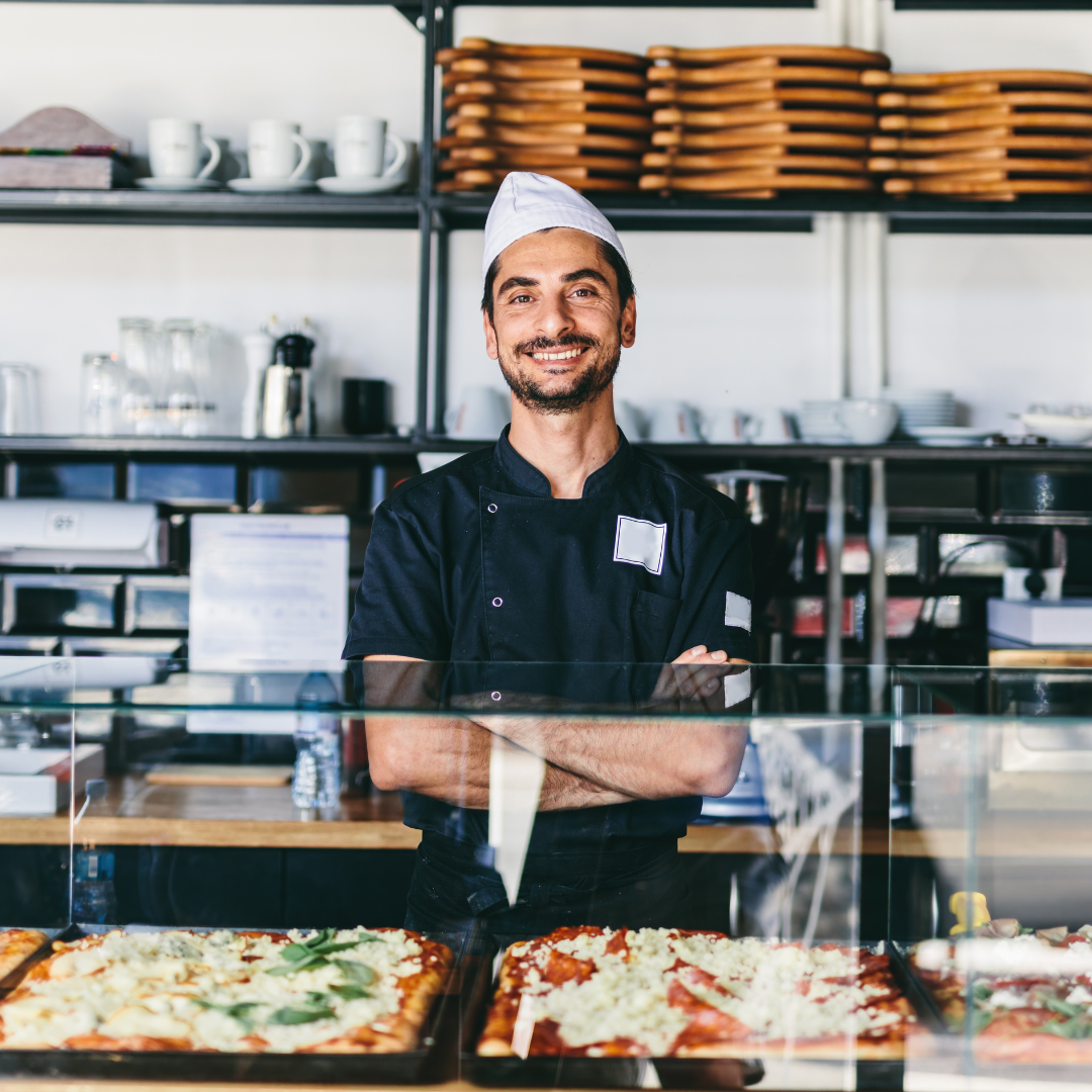 restaurant owner at a pizza restaurant, smiling and standing with his arms crossed